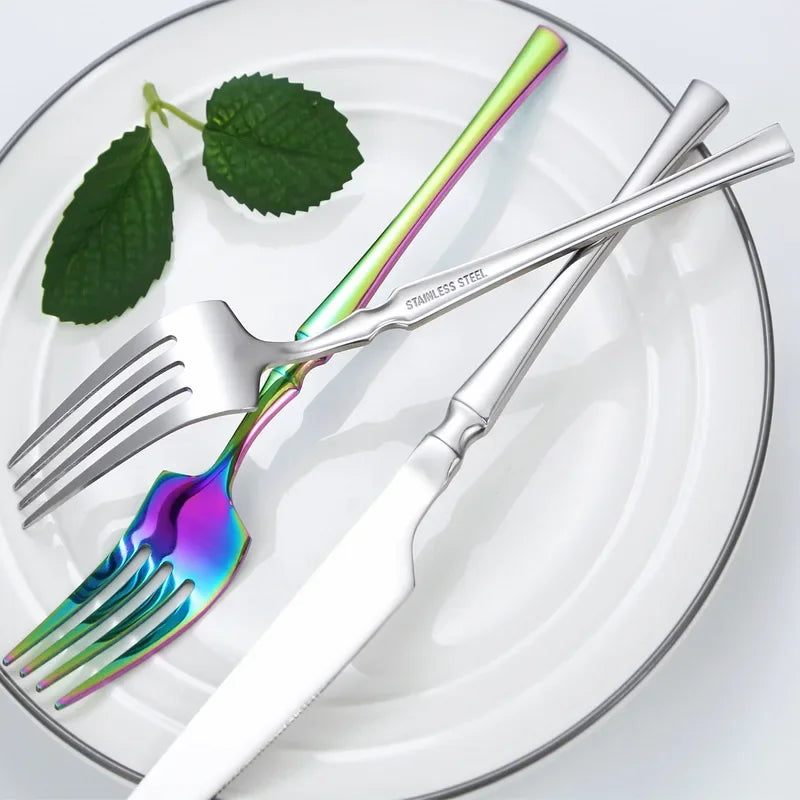 Stainless steel dinnerware set including colorful forks and knife on a plate with leafy garnish.